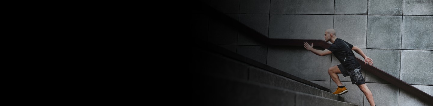 Cropped 2880x1100 left black gradient of Focussed runner man jogging on stairs