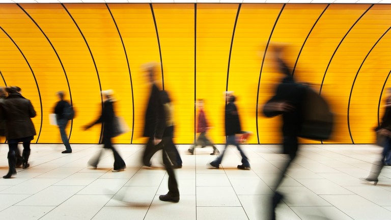 blurred and defocused people walking in orange subway